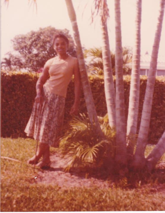 Celia standing under palm trees