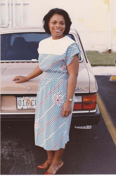 Celia in a blue dress beside a car